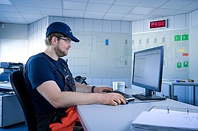 Ein Mitarbeiter von Veolia ist an seinem Arbeitsplatz in der Leitwarte des Wasserwerks. Er sitzt konzentriert vor seinem Computerbildschirm.