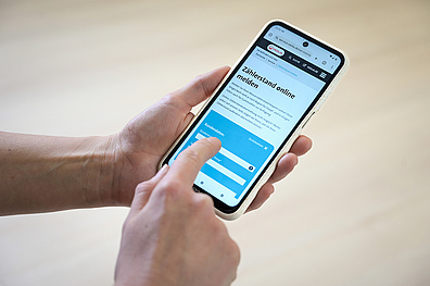 Nahaufnahme von Händen, die ein Smartphone halten und auf der Veolia-Webseite den Wasserzählerstand online über ein Formular melden