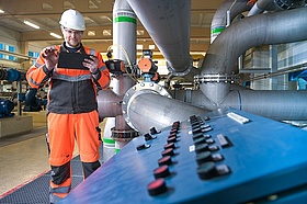 Ein Mitarbeiter von Veolia steht in einem Wasserwerk vor einer Filterrückspülanlage. Er gibt Daten in sein Tablet ein. Die große technische Anlage im Hintergrund verdeutlicht die Komplexität der Wasseraufbereitung.