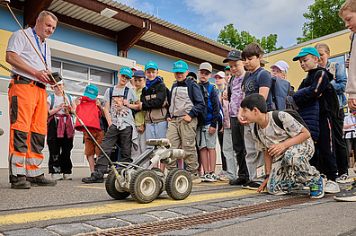 Veolia-Mitarbeiter zeigt am Weltumwelttag den Kindern einen Rohrreinigungsroboter.