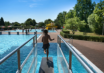 Sommerliche Szene im Muldentalbad Kleinbothen. Ein Kind springt von einem Sprungbrett in das Wasserbecken. 