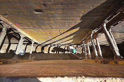 Einblick in eine 5 Meter tiefe Baugrube in der ein Bauarbeiter steht.