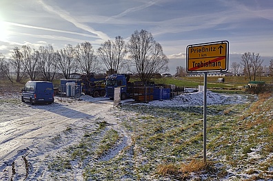 Das Ortseingangsschild von Prießnitz. Im Hintergrund eine Baustelle mit die leicht mit Schnee bedeckt ist.