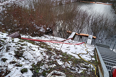 Ein Rückhaltebeckens im Winter. Die Wasserfläche des Beckens ist deutlich zu erkennen. Am Rand des Beckens und in der umliegenden Landschaft ist eine leichte Schneedecke sichtbar.