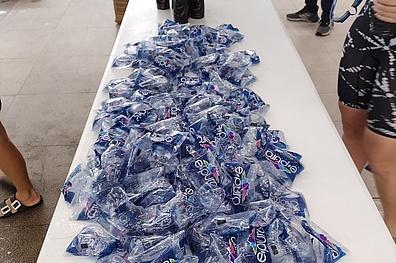 Ein weißer Tisch auf dem mehrere Packungen abgefülltes Trinkwasser liegen.